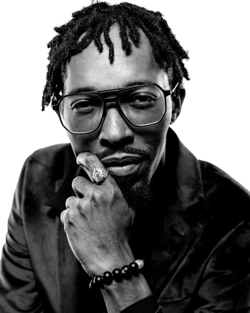 Black and white portrait of David in glasses, hand to his chin